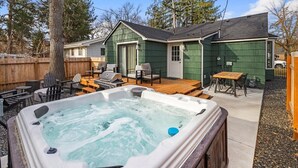 A backyard with a hot tub, outdoor seating, and a wooden deck.