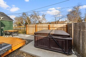 Un jardin avec une terrasse en bois, un barbecue et un grand banc en bois.