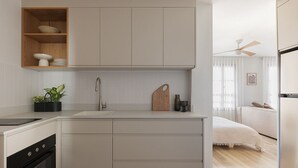Een moderne keuken met een ingebouwde oven, een spoelbak en een houten plank met servies.