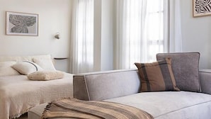 Een moderne, goed verlichte slaapkamer met een groot bed, een sofa en een plafondventilator.