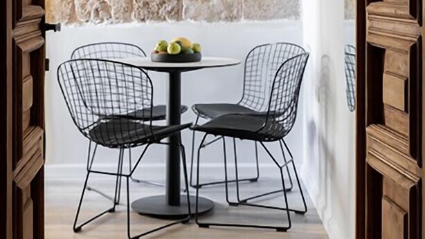 Een eethoek met een stenen muur, een ronde tafel en twee stoelen met een metalen frame.