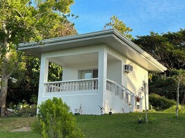 Una casa de dos pisos con balcón, rodeada de vegetación.
