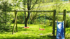 A playground with swings and a slide. - Holiday home Ockholm (Ockholm)