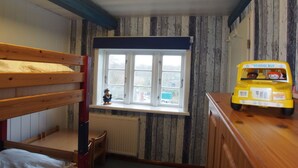 A child's bunk bed with a window above, a radiator below, and a toy school bus on a dresser. - Holiday home Ockholm (Ockholm)