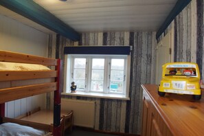 A child's bunk bed with a window above, a radiator below, and a toy school bus on a dresser. - Holiday home Ockholm (Ockholm)