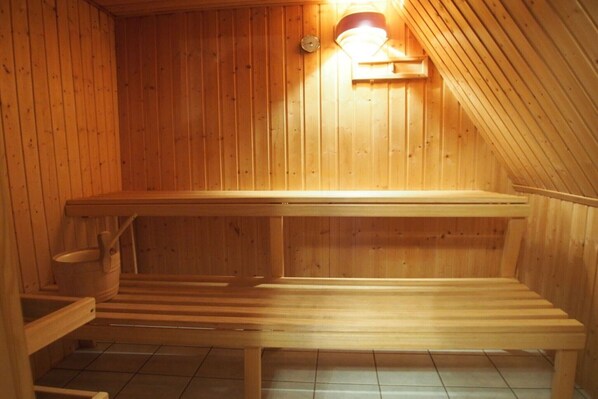 Una sauna de madera con bancos y un calentador fijado a la pared.