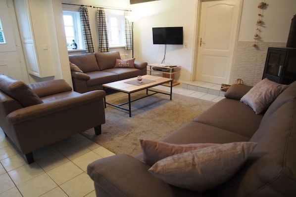 A living room with brown sofas, a coffee table, a flat-screen TV, and a door with a decorative wall hanging.