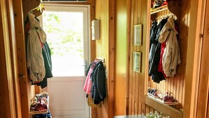 Ein Holzbodenkorridor mit Fliesenboden, einem Kleiderständer, einem Schuhregal und einem kleinen Tisch mit Blumentöpfen.