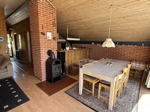 Un intérieur rustique avec une cheminée en briques, une table à manger en bois et un coin cuisine.