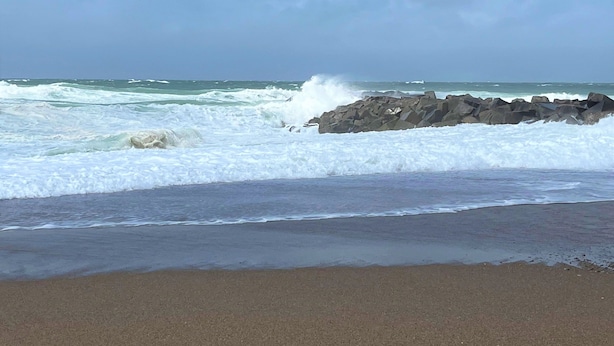 Ein Strand mit brechenden Wellen an den Felsen.