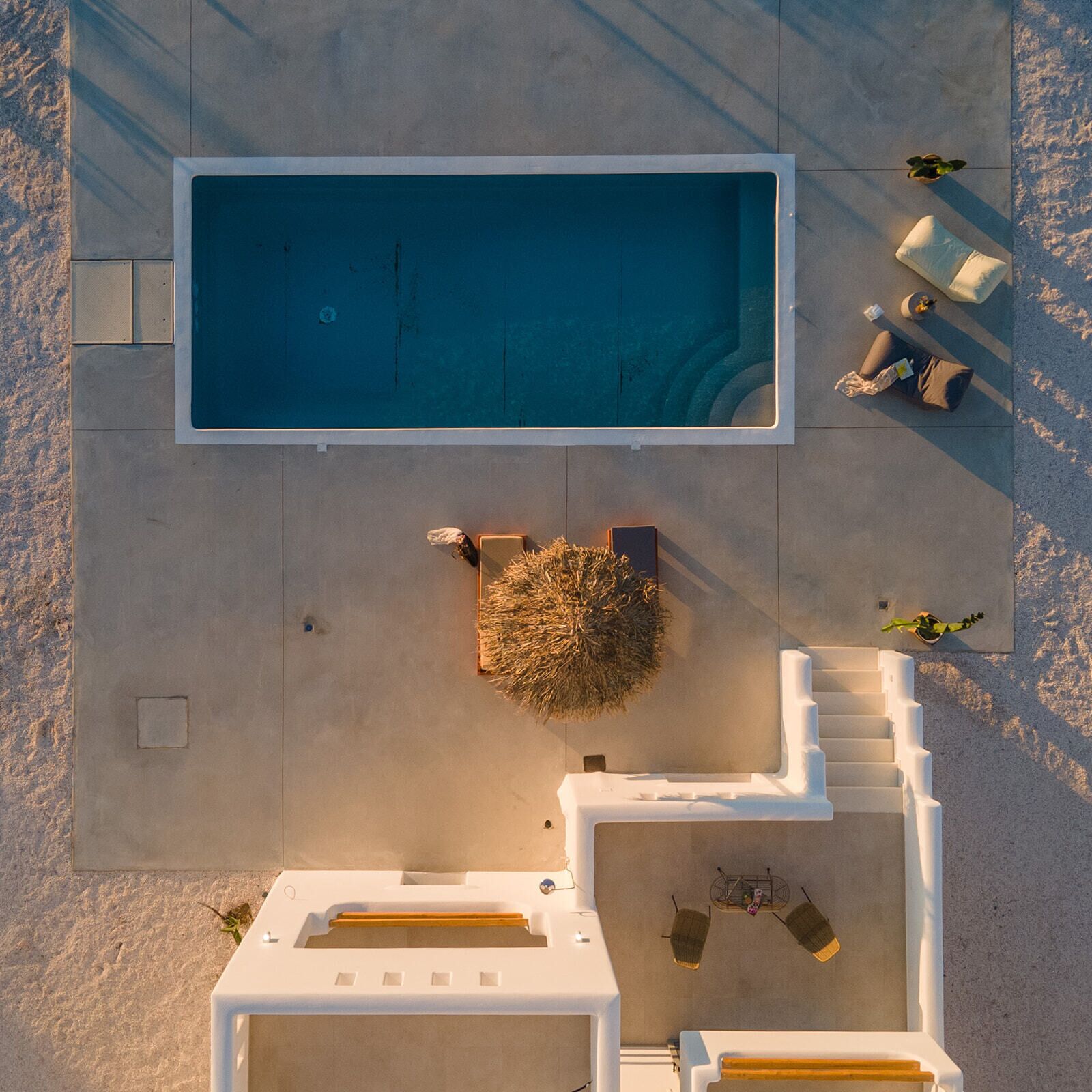 Vista aérea de una piscina con sillones de descanso cercanos y un pequeño jardín.