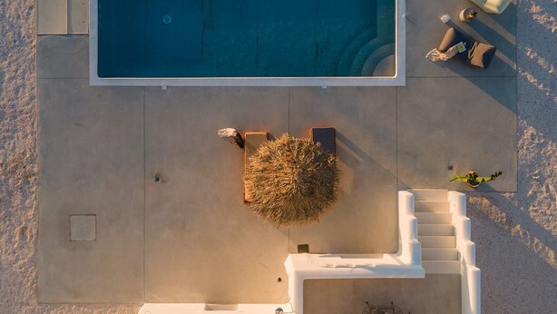 Vue aérienne d’une piscine, avec des chaises longues à proximité et un petit espace aménagé en jardin.