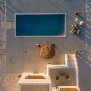 Vista aérea de una piscina con sillones de descanso cercanos y un pequeño jardín.