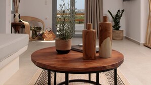 Un salon moderne avec une table ronde en bois, un canapé et une grande fenêtre donnant sur l’extérieur.