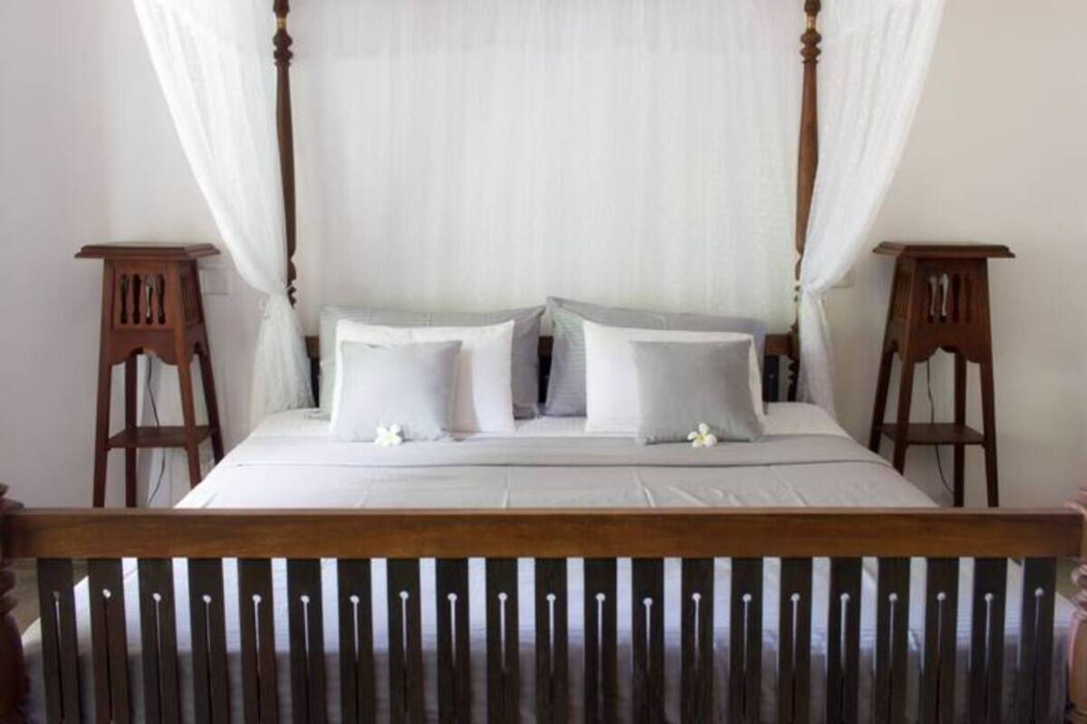 Uma cama de dossel com lençóis brancos e cortina.