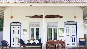 A covered outdoor seating area with a bench, chairs, and a table.