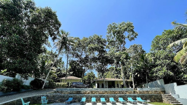 A swimming pool with lounge chairs and a stone wall.