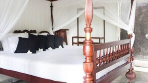 A four-poster bed with a canopy, white bedding, and dark pillows.