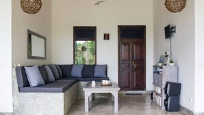 A living area with a sectional sofa, a coffee table, a bookshelf, and a door.