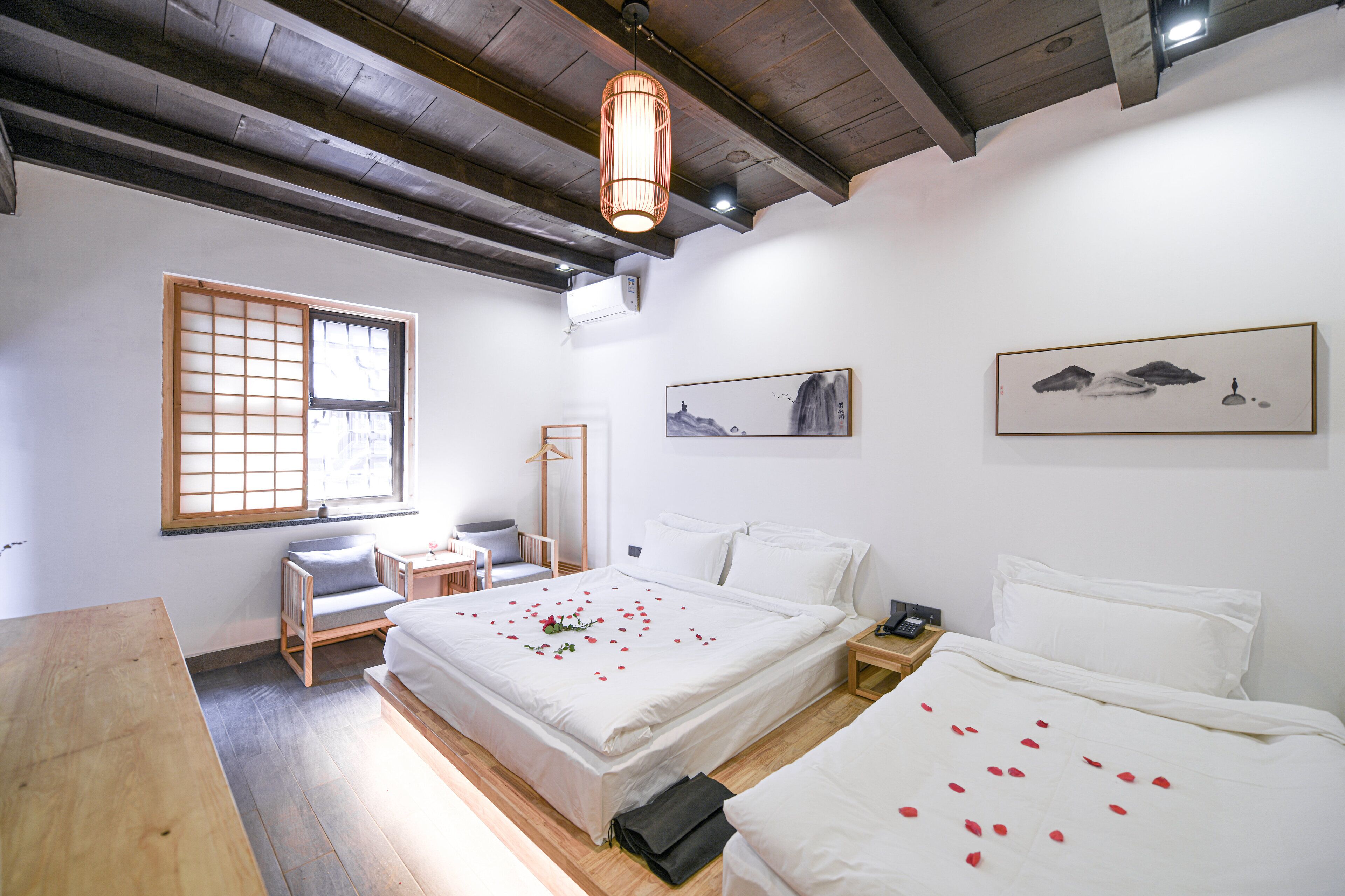 Una habitación de hotel con piso de madera, una cama grande con ropa blanca, un escritorio con una silla y una ventana con vistas al exterior.
