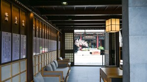 Et traditionelt japansk interiør med tatamimåtter, lave træborde og udsigt til kirsebærblomster udenfor.