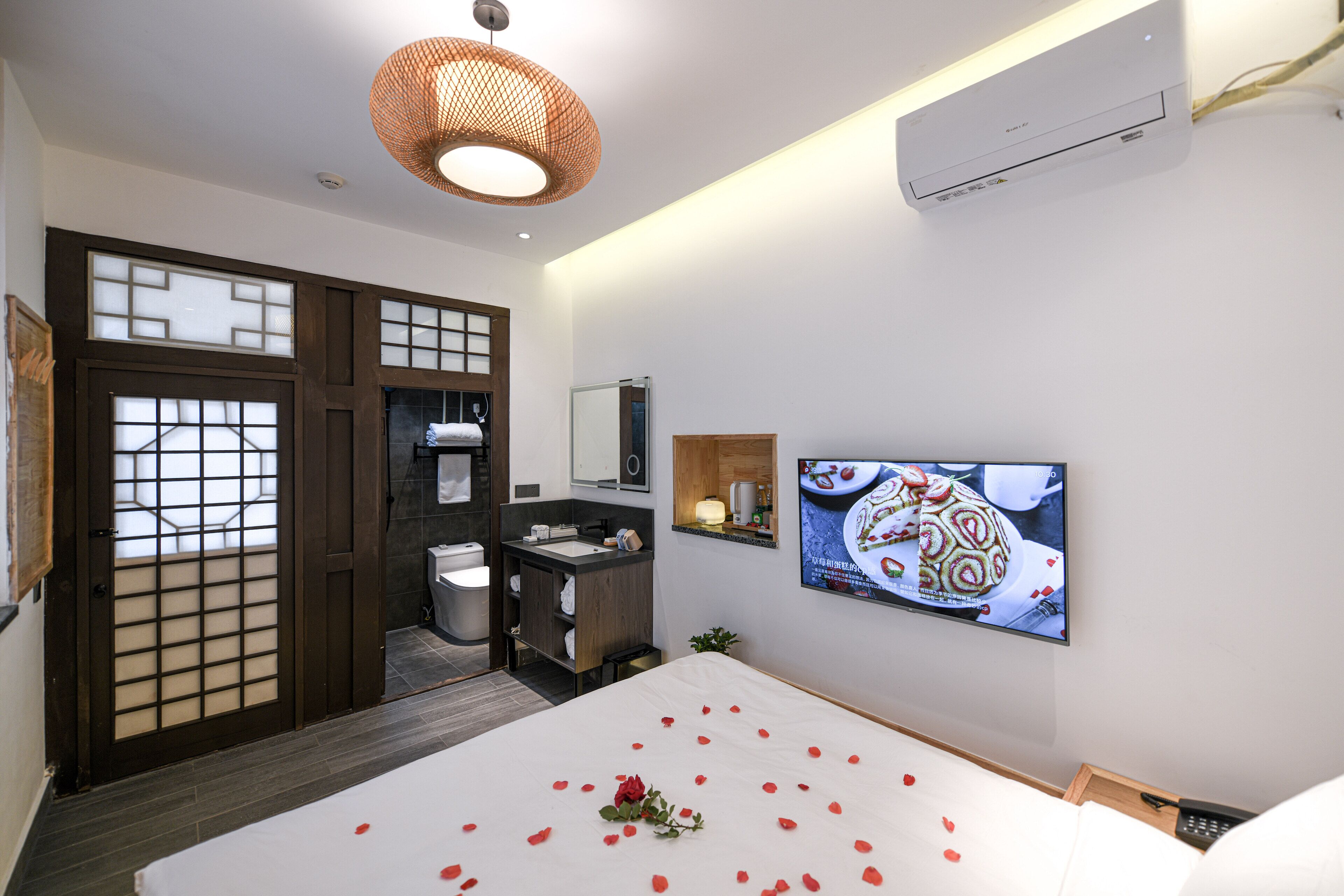 A hotel room with a bed, a TV, a bathroom, and a traditional Japanese sliding door.
