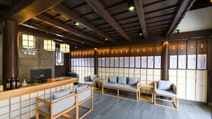 Et traditionelt japansk interiør med tatamimåtter, møbler af træ og et receptionsområde med disk og siddepladser.