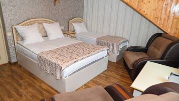 A bedroom with two beds, a wooden ceiling, and a small table.