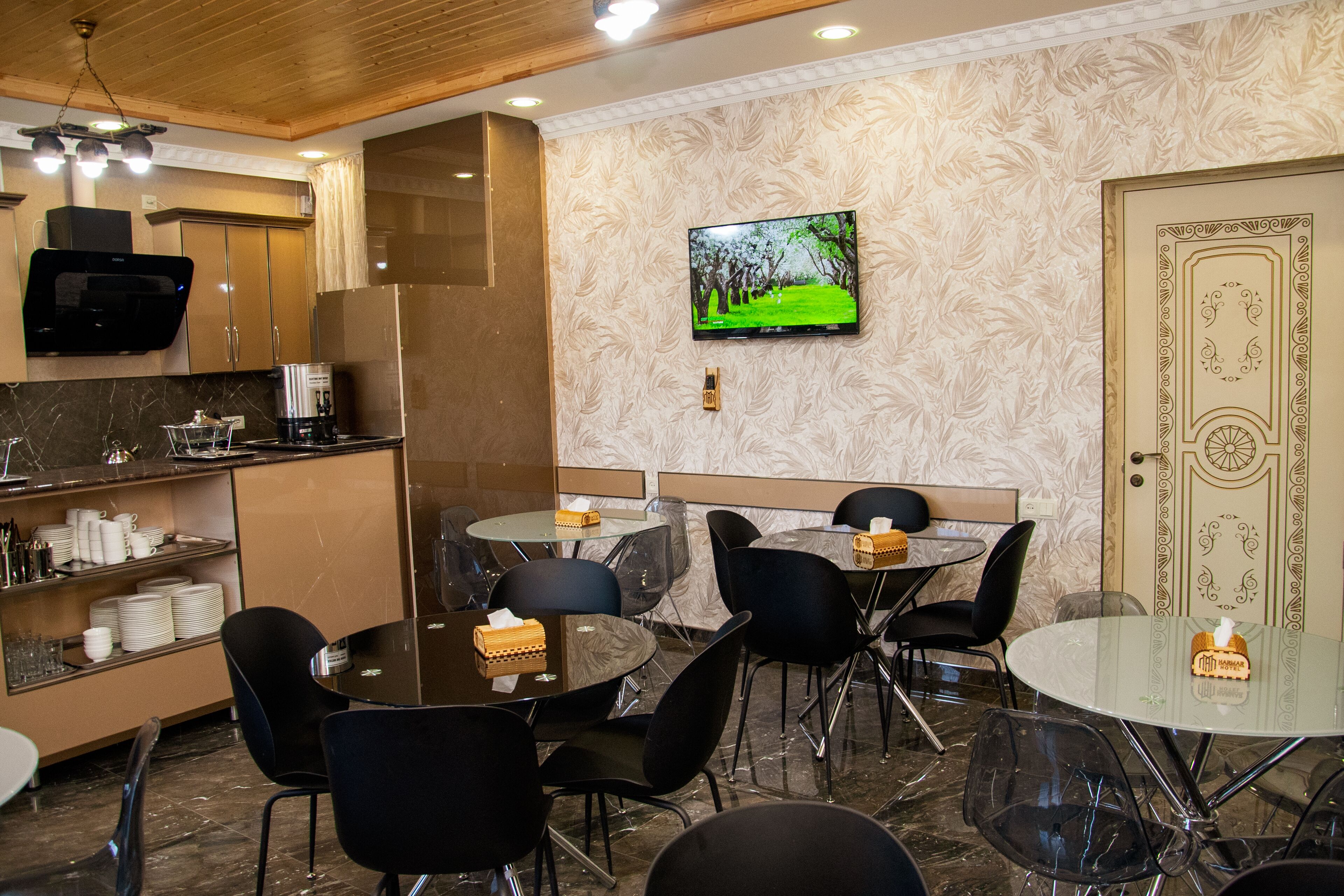 A modern dining area with a TV, wooden cabinets, and a patterned wall.
