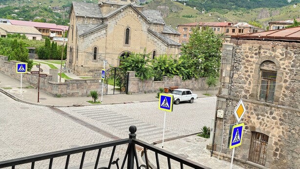 A historic building with a bell tower, a paved street, and pedestrian crossing signs. - Har-Mar Hotel (Goris)