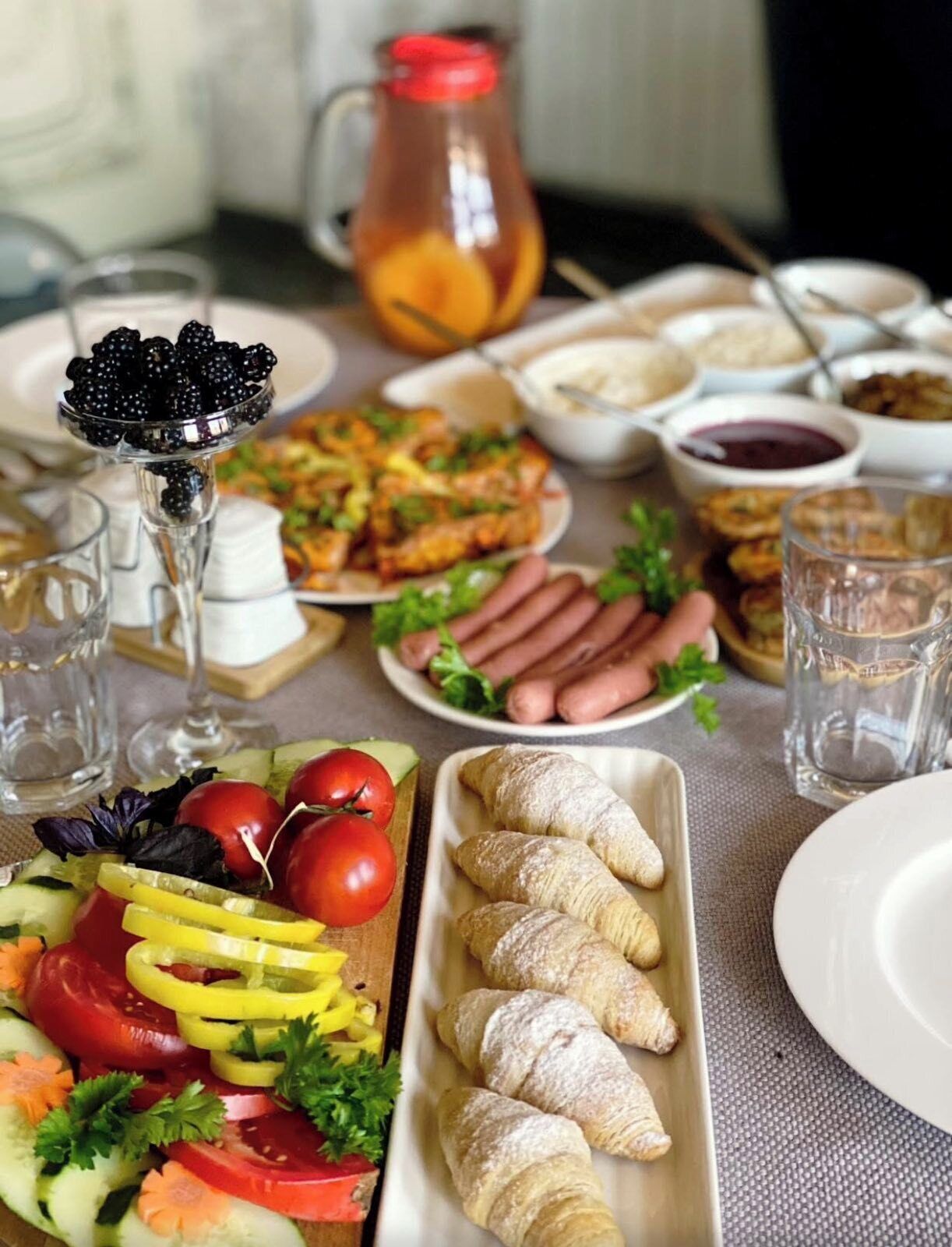 A table with various food items, including a salad, hot dogs, and pastries.