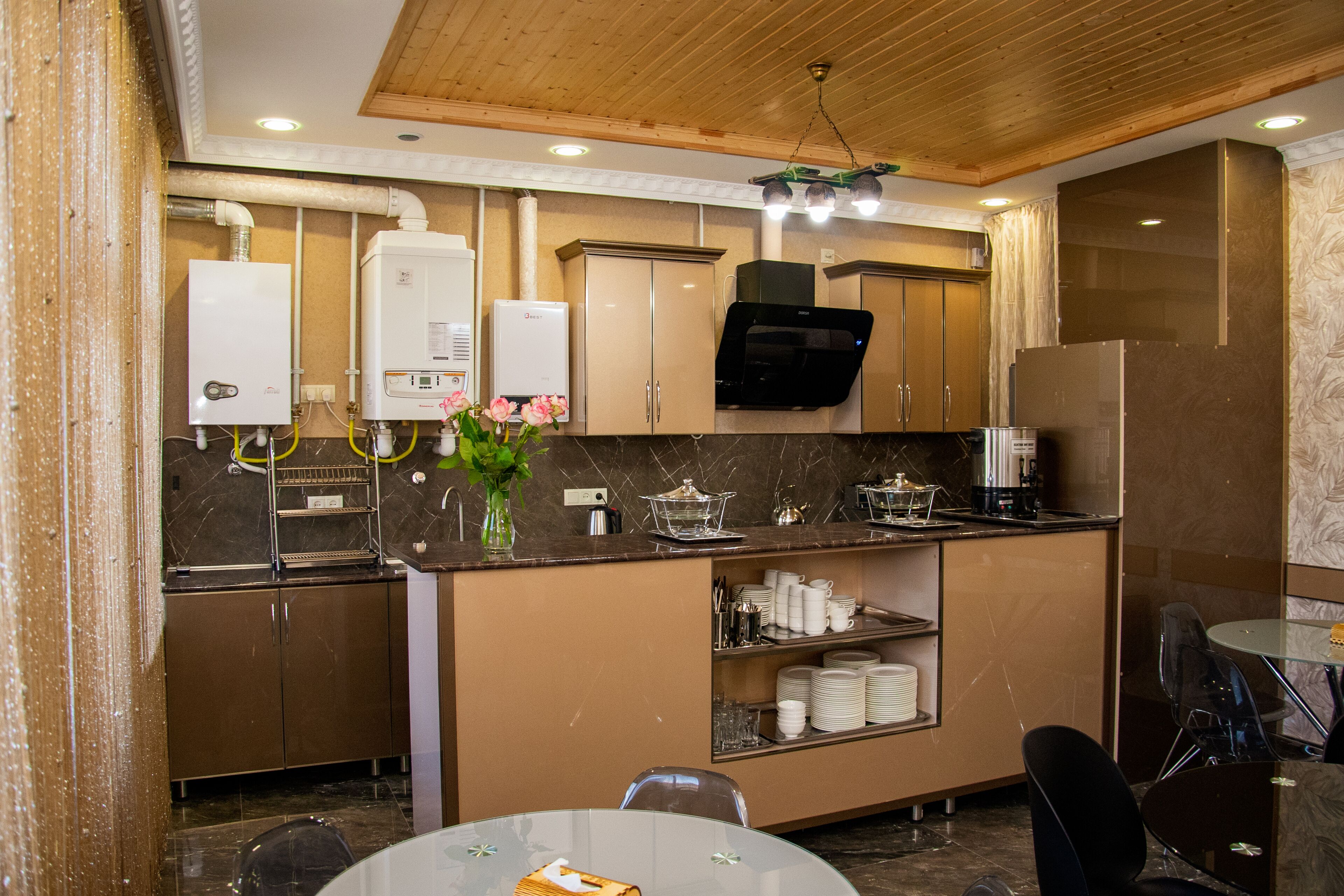 Una cocina moderna con electrodomésticos integrados, un comedor con mesa de vidrio y techo de madera.