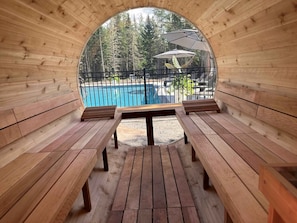 Une terrasse en bois avec des bancs et une vue sur la piscine.