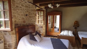 Ein Schlafzimmer mit einem großen Bett, einem Holzschrank, einem kleinen Tisch und einem Spiegel.