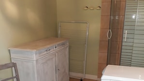 Ein Zimmer mit einem weißen Schrank, einem Stuhl, einem Metallgestell und einem weißen Gerät.