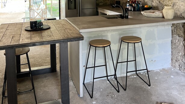 A rustic kitchen with a wooden ceiling, a large island with stools, and a view of the outdoors. - Maison & Pool in the Bourgogne (Saint-Nizier-sur-Arroux)