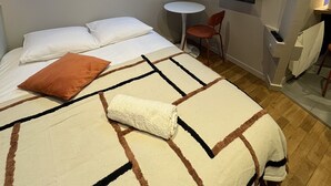 A small, cozy room with a bed, a chair, a small table, and a TV. There is a skylight above the bed. - La Madeleine Jolie Studio en Hyper Centre (Rennes)