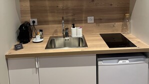 A compact kitchen with a stainless steel sink, a coffee maker, and a tablet on the counter. - La Madeleine Jolie Studio en Hyper Centre (Rennes)