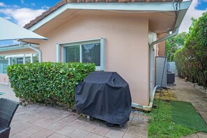 Una casa con una parrilla techada, una ventana y un seto.
