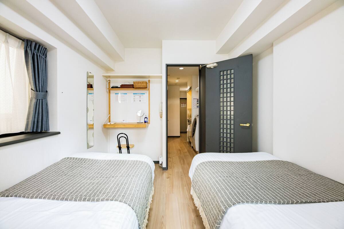 A hotel room with two beds, a mirror, a desk, and a wardrobe.