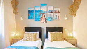 Habitación de hotel con dos camas, cada una con cabecera, un cuadro grande sobre las camas y dos lámparas de noche.