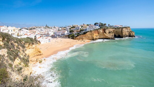 Un pueblo costero con edificios sobre un acantilado con vista a la playa.