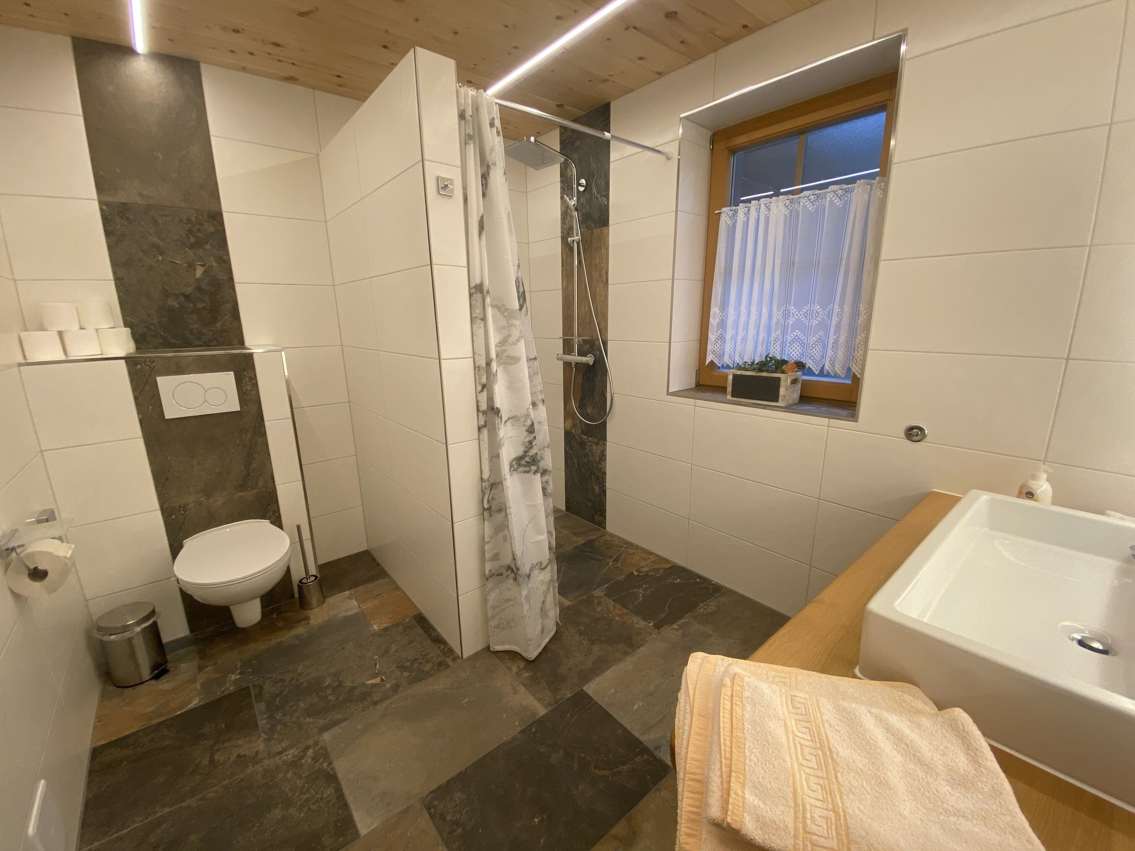 Een badkamer met douche, toilet en bad.