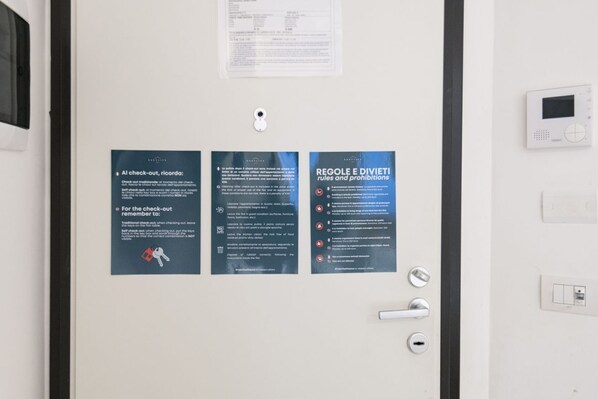 Una puerta con tres carteles informativos: uno sobre los procedimientos de salida, uno con normas y prohibiciones, y uno con una lista de artículos prohibidos.