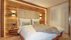 Une chambre à coucher moderne avec une tête de lit en bois, deux lampes de chevet et un grand lit recouvert de linge de lit blanc.