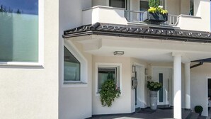Une entrée d’immeuble avec un porche abrité, une porte portant le numéro 69 et des plantes en pot.