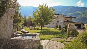 Une maison avec une vue sur les montagnes, entourée de gros rochers et de verdure.