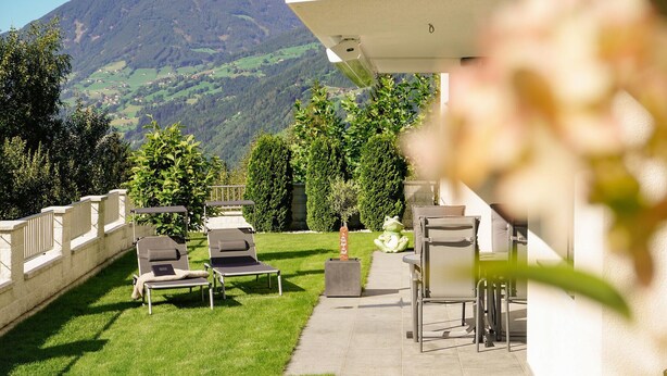 Une terrasse avec des chaises longues et une petite table, offrant une vue sur un paysage montagneux.
