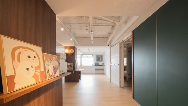 A modern interior with a wooden reception desk, framed artwork, and a view into a kitchen area. - Cattail pocket Inn (Taipei)
