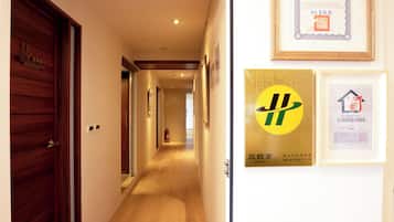 Een hotelgangen met houten deuren, een brandblusser en ingelijste certificaten aan de muur.